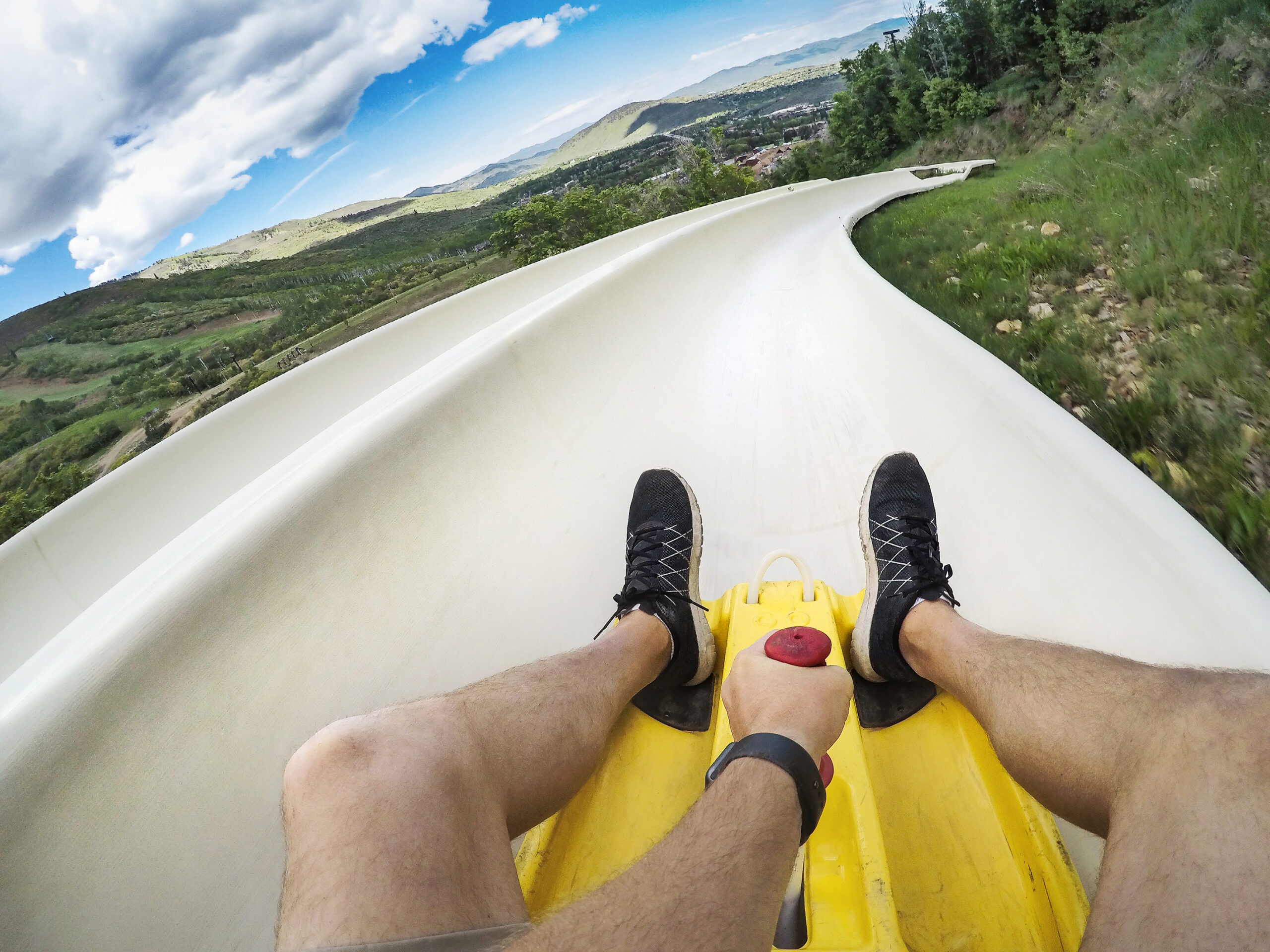 Point of view photo of a man riding down an downhill alpine slide on a fun summer vacation in the mountains